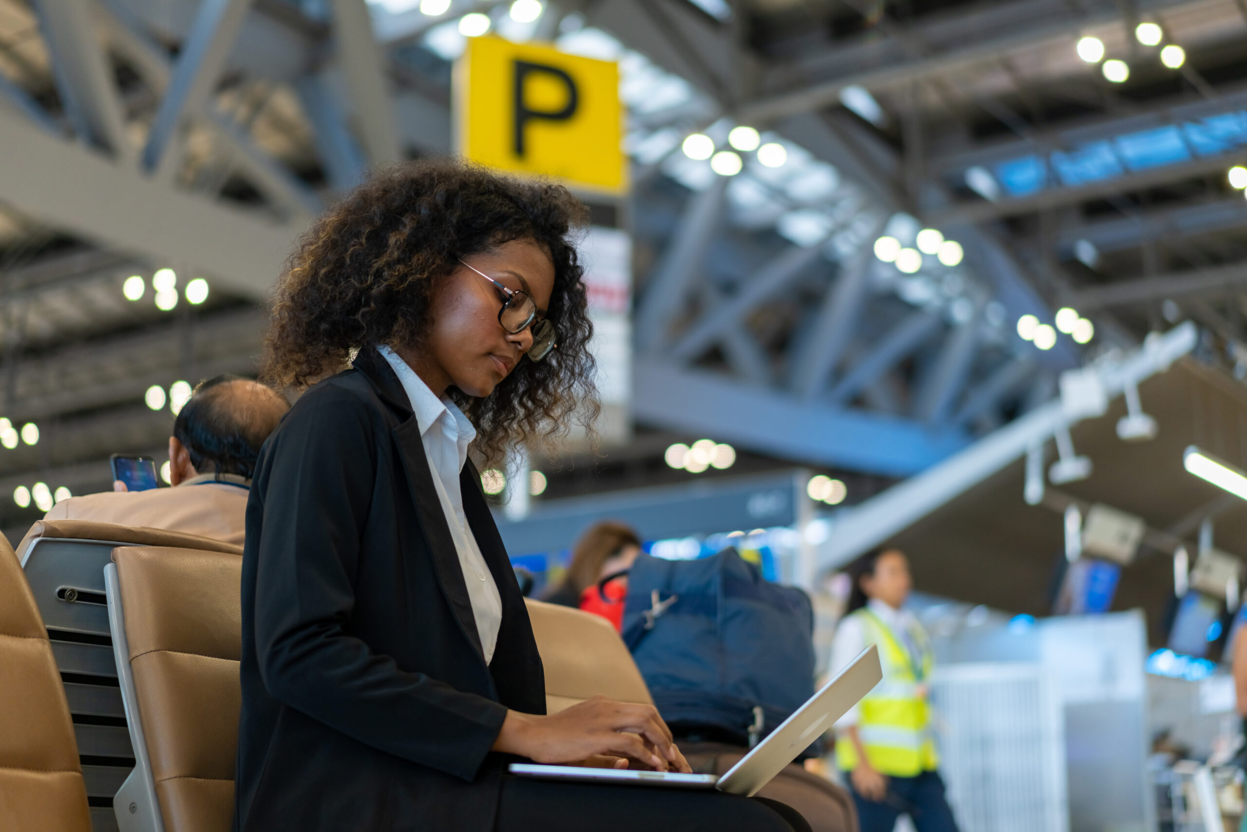 Businesswoman remote working on laptop computer at airport terminal.