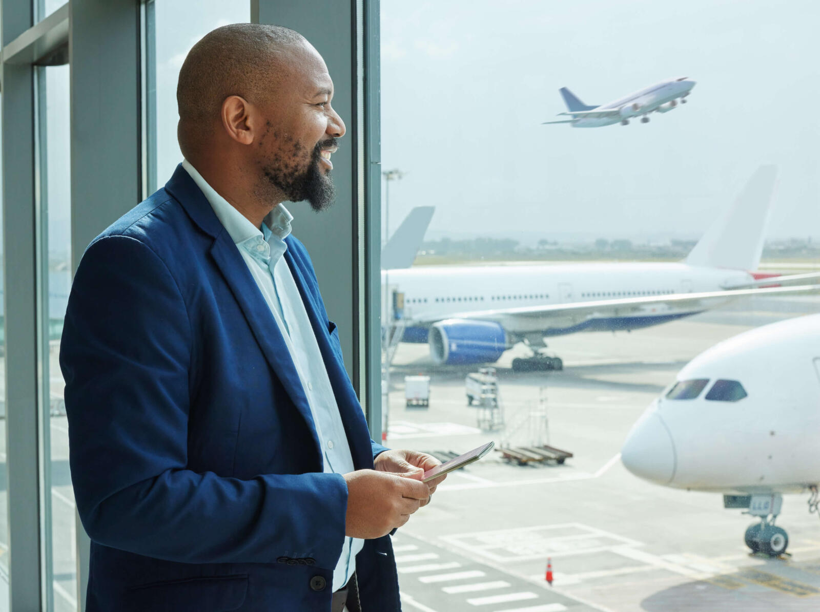 black-man-airport-smartphone-travel-with-communication-airplane-smile-business-trip-looking-out-window-waiting-flight-with-transportation-journey-airline-with-mobile (1)